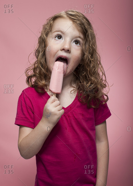 Redhead girl eating fruity ice cream bar