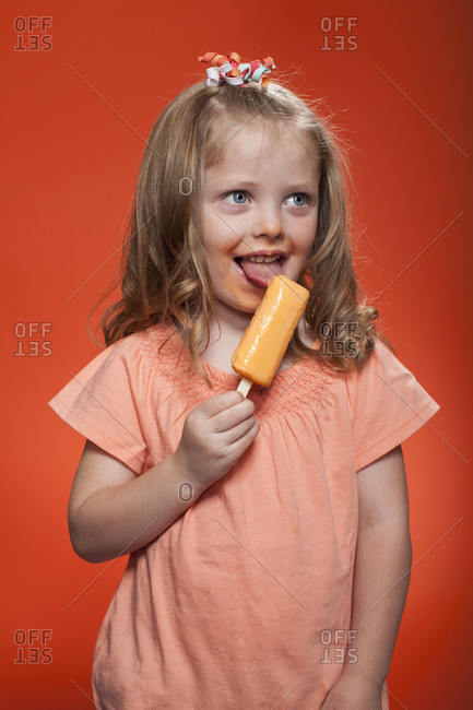 Little, long haired girl eating fruity ice cream bar