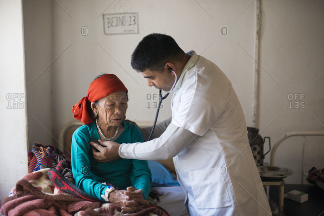 A doctor examines an old woman with a stethoscope in a rural hospital in Nepal
