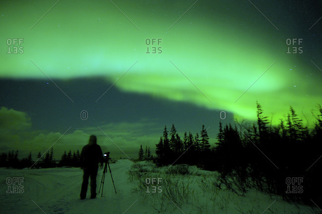 A photographer watches as the northern lights dance in the sky