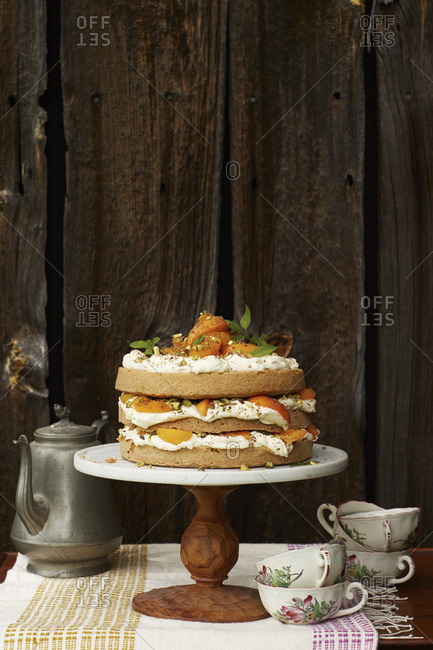 Layer cake with peaches, whipped cream and pistachios