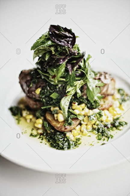 Roasted meat with corn, garnished with basil