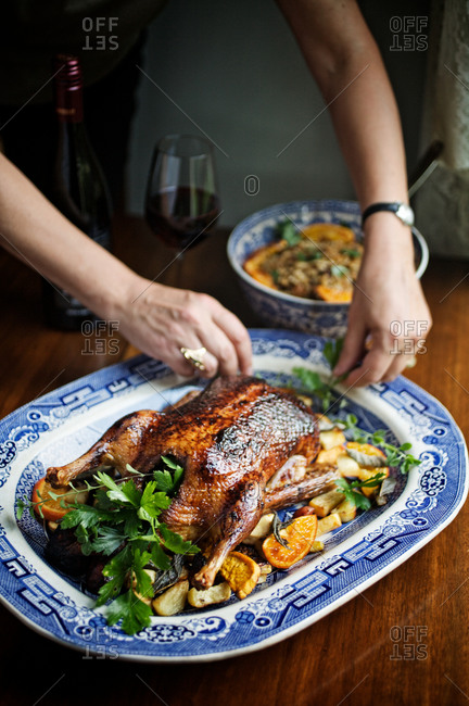 Woman arranging classic roasted chicken with side dish