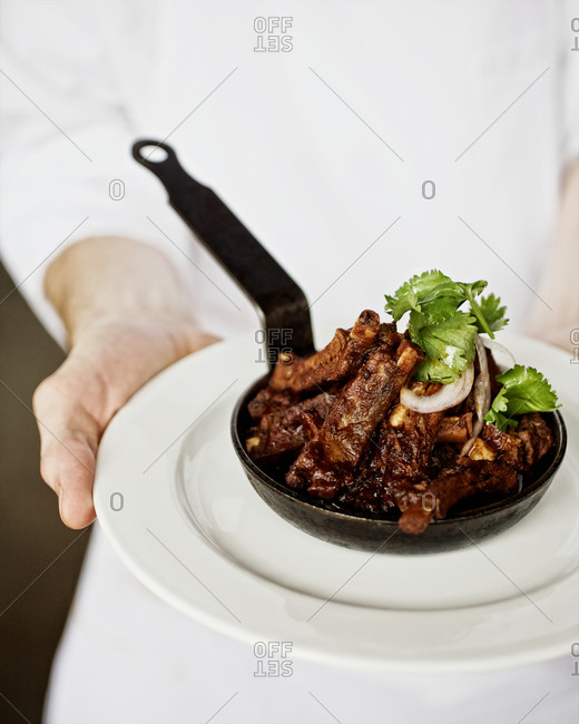 Chef holding a portion of glazed pork ribs