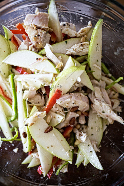 Close up of warm chicken salad with peppers, pears and toasted pine nuts