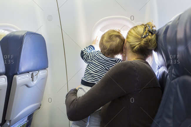 Caucasian mother and baby looking out airplane window