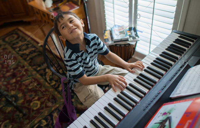 A boy plays the keyboard piano in the living room.