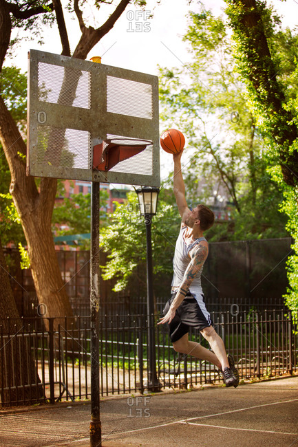 Young man jumping to slam dunk a basketball
