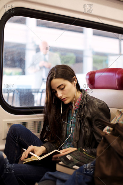 Young woman traveling by train and listening music