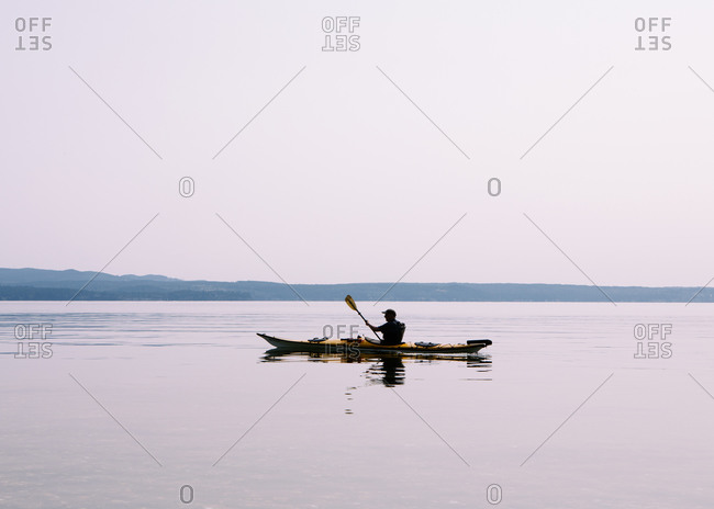 Man sea kayaking calm waters of Puget Sound, dusk