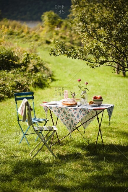 A table set outside in the country with a peach dessert