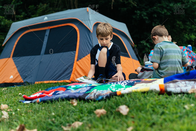 Boys reading magazines at a camping tent