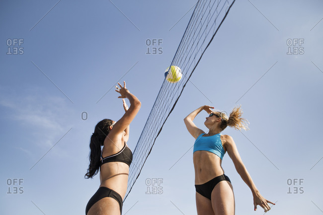 Low angle view of girls hitting the volleyball over the net