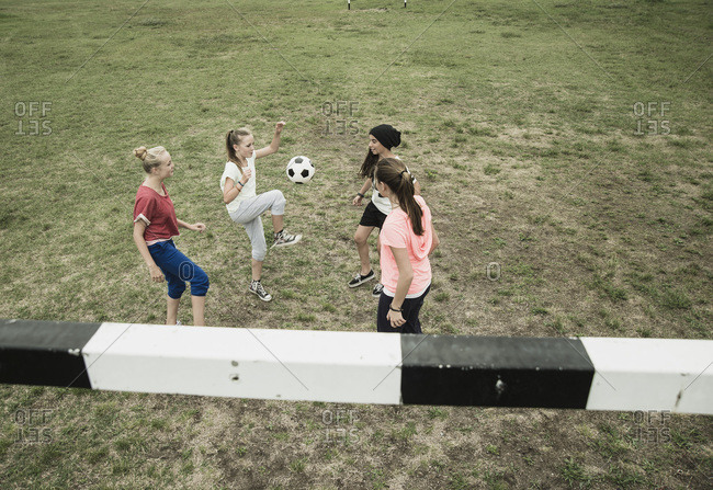Four teenage girls playing soccer on a football ground