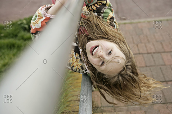 Happy young girl hanging upside down on a railing of a stairway