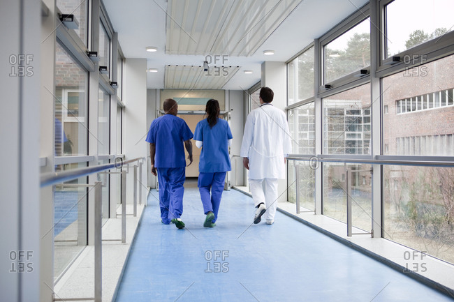 Three medical professionals walking together down a corridor in a hospital