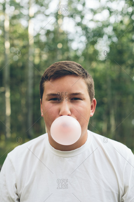 Teenage boy chewing bubble gum and blowing large bubble