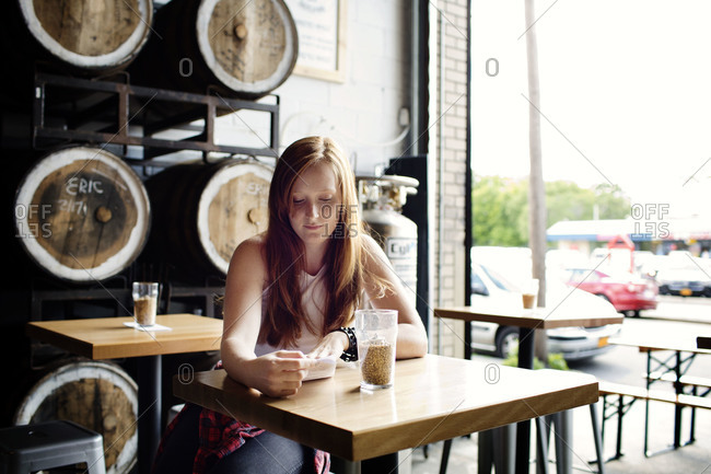 Young woman reading the drinks menu in a brew pub