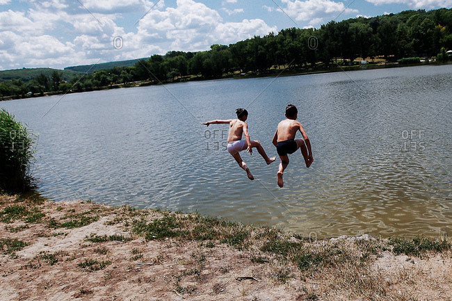 Two children jump into a river in Moldova on a hot summer day