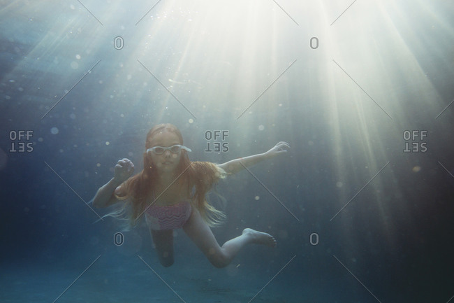 Long haired girl floating underwater on a sunny day