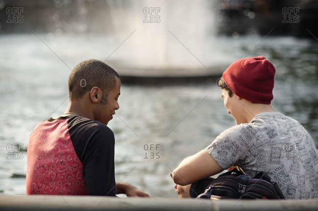 Rear view of boys having a conversation by a fountain