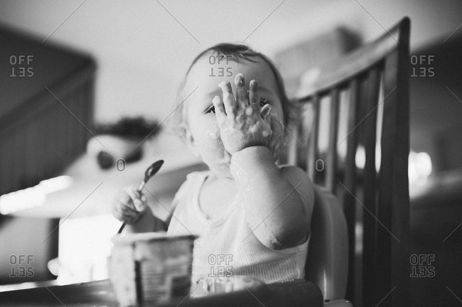 Little boy licking yogurt off his hand