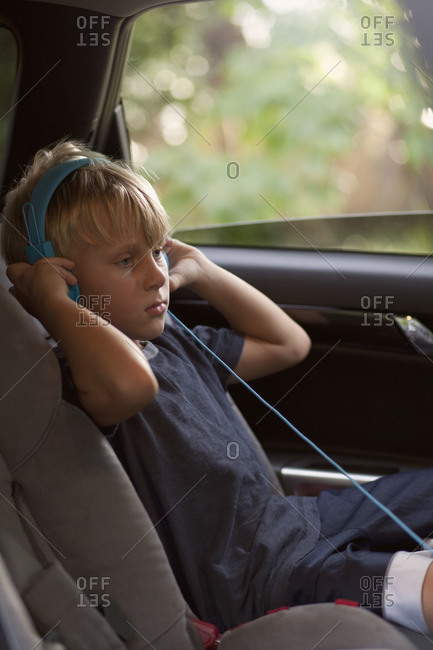 Boy sitting in back seat of car with headphones