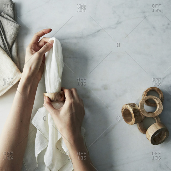 Woman placing a wooden napkin ring on a napkin