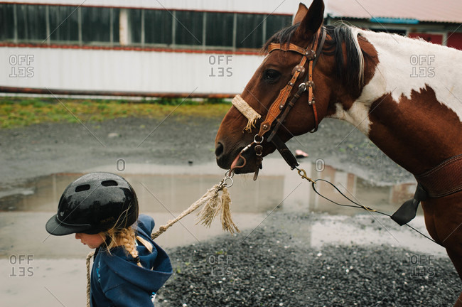 Close up of little girl leading a horse by a rope
