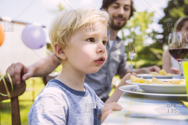 Boy eating pasta with family at garden table