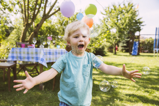 Boy trying to catch soap bubbles in garden