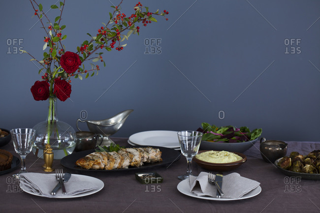 Table set for thanksgiving with a bouquet of red roses