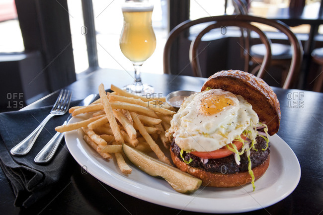 Sunny side up burger served with pickles, chips and beer