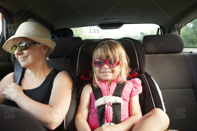 Young girl and grandmother sitting in the backseat of a car