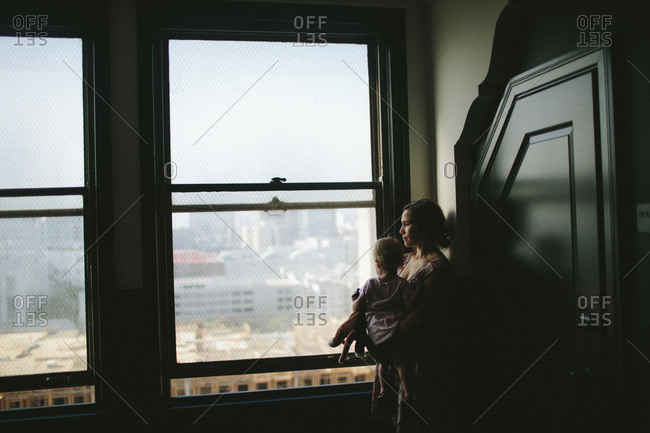Woman staring out of a window while holding her daughter