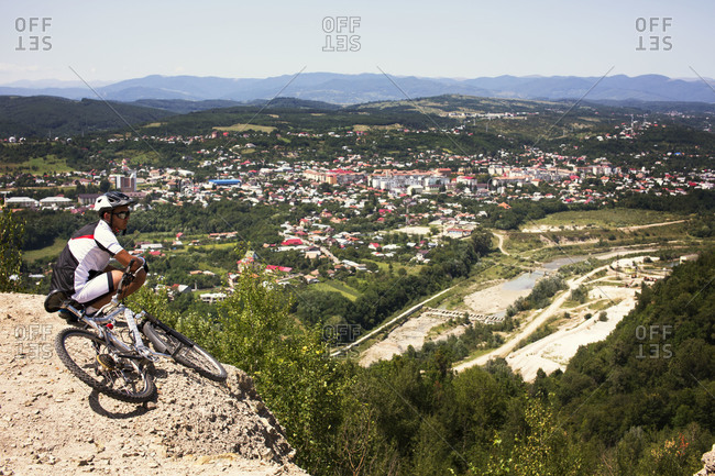 Man with mountain bike overlooking town in valley