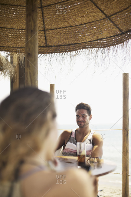 Man seen over woman\'s shoulder in bar of tropical resort