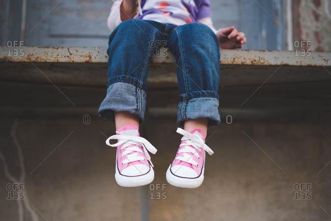 Low section view of girl wearing jeans and pink athletic shoes