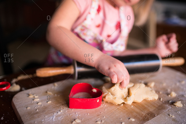 Girl making heart-shaped cookies for Valentine\'s Day