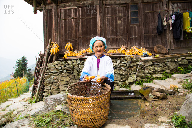 Elderly woman shelling corn cobs in Guanxi, China