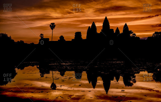 The temples of Angkor Wat silhouetted against a dramatic orange sunrise, Cambodia