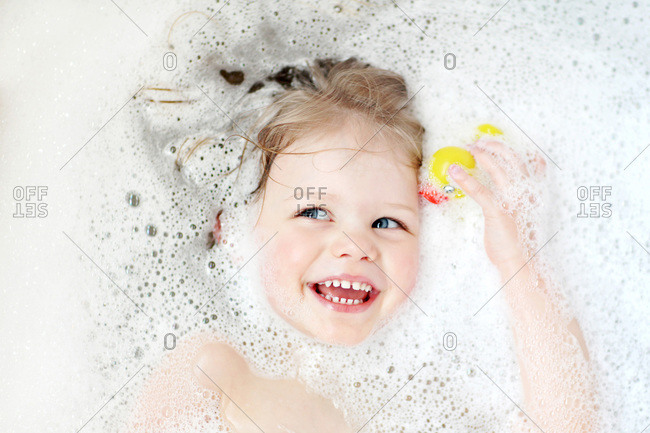 Top view of little girl with a rubber duck in the bathtub