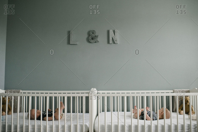 Twins lying in their separate cribs