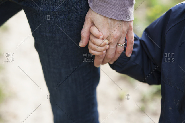 Son holds mother\'s hand as they go for a walk together