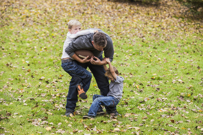 A father playing football with his boys in a park