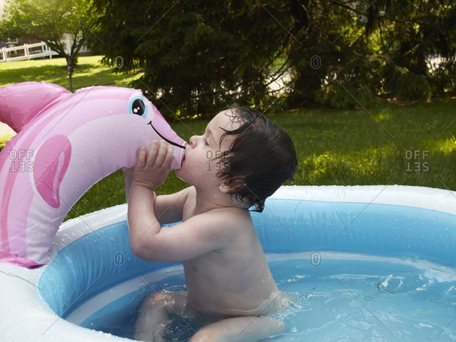 Young boy kissing an inflatable dolphin of a kiddie pool