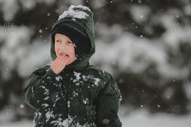 Boy in snowsuit eating snow outside