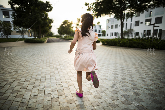 Young Vietnamese girl runs through a private drive as the sunsets in a suburban housing complex in Ho Chi Minh City, Vietnam