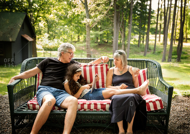 Elderly couple resting with their granddaughter on an outdoor couch