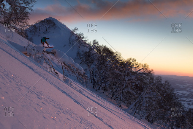 Woman snowboarding at sunset in Japan
